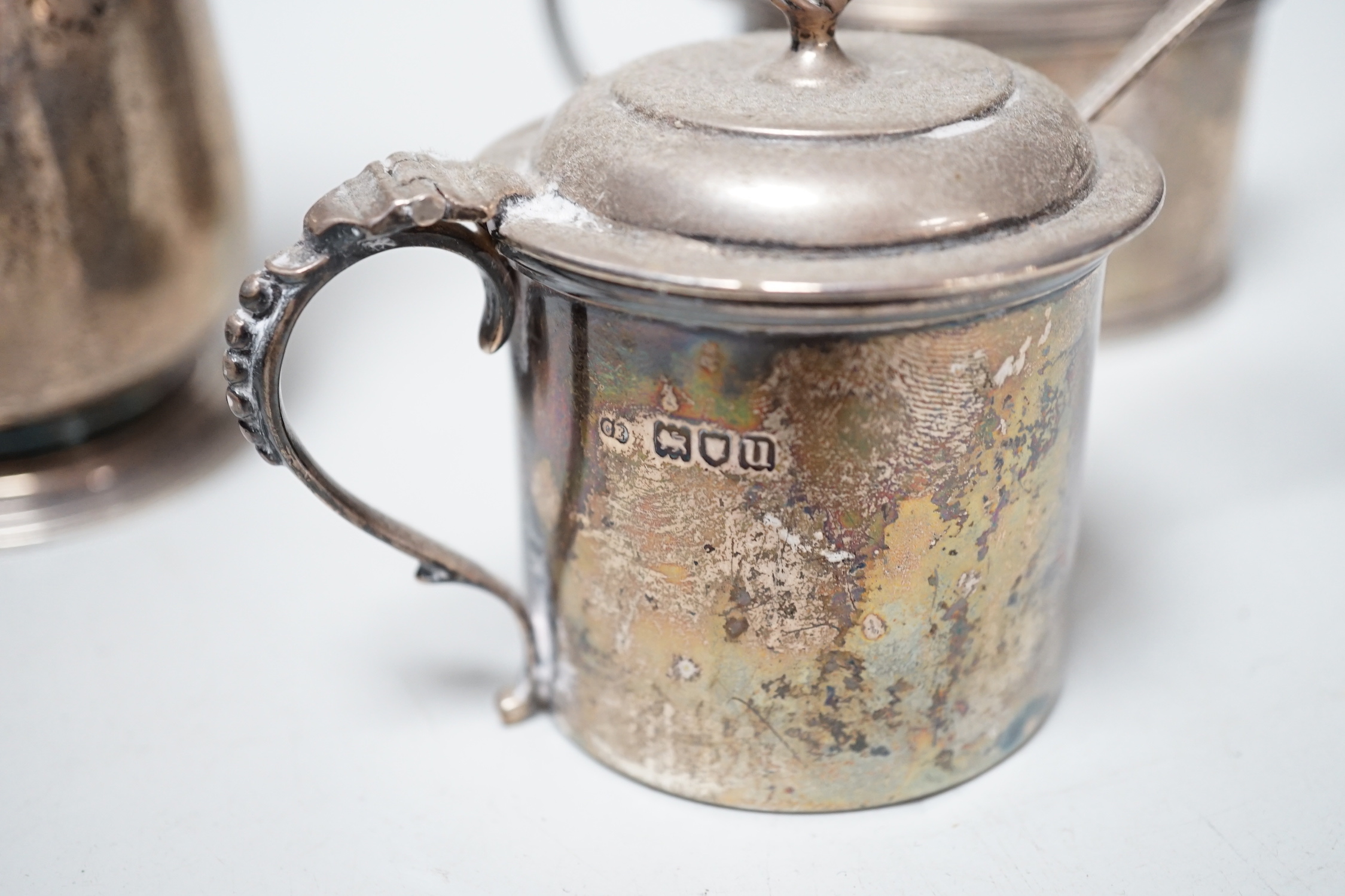 An early 20th century silver hot water pot and two silver mustard pots.